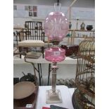 A Victorian silver plated oil lamp with cranberry glass font and shade