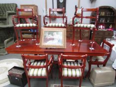 A mahogany extending dining table and 6 brass inlaid elbow chairs