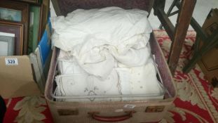 A suitcase with linen including Christening gowns