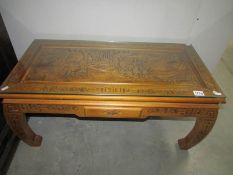 An oriental carved coffee table with glass top and drawer