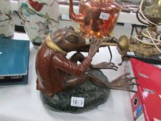 A cold painted bronze of a seated toad playing a woodwind instrument