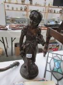 A bronze figure of a lady carrying an cockerel,