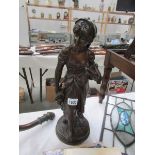 A bronze figure of a lady carrying an cockerel,