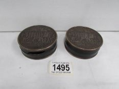 A pair of round metal and wood snuff boxed 'Landing in America' a/f