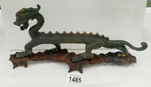 A patinated bronze dragon on hardwood base