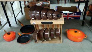 A set of 5 cast iron pans on stand and other pots and pans including Le Crueset