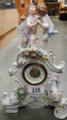 A ceramic mantel clock surmounted cherubs