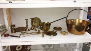A shelf of brassware including Victorian jam pan, saucepan & miners lamps etc.