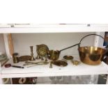 A shelf of brassware including Victorian jam pan, saucepan & miners lamps etc.