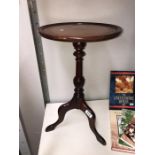A dark wood stained tripod wine table with leather insert in top