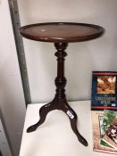 A dark wood stained tripod wine table with leather insert in top