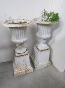 A pair of metal garden urns on stands