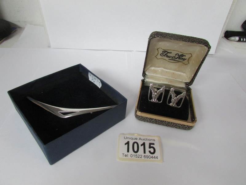 A pair of silver cuff links decorated with eagles and a Danish silver brooch