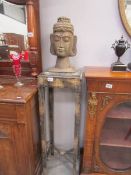 A carved wood Buddha head on a wooden stand