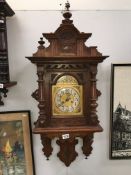 An oak wall clock with brass dial