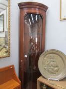 A corner cabinet with concave glass