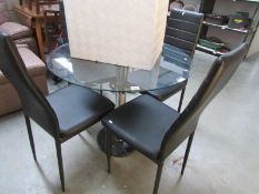 A glass top table and 4 faux leather chairs