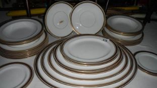 A Royal Doulton gold banded part dinner set with platters,