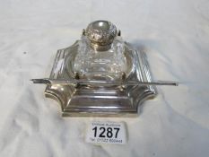 A silver ink stand with glass inkwell and silver dip pen