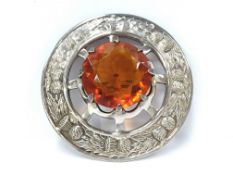 A large white metal Celtic brooch set large amber coloured stone