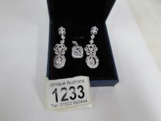 a pair of white stone set pendant earrings and a white stone set pendant in silver