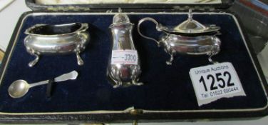 A cased 3 piece silver condiment set with liners (1 liner a/f) all with different hall marks (1