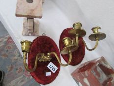 A pair of double brass candle sconces on velvet backs