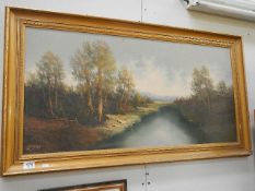 A large gilt framed oil on canvas signed 'Koenig' of a tree lined river