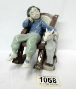 A Lladro figure of a boy asleep in a rocking chair