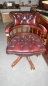 A reproduction swivel office chair with maroon leather upholstery