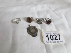 A silver watch fob and 4 silver rings