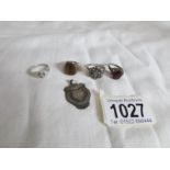 A silver watch fob and 4 silver rings