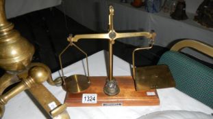 A set of small brass scales on wooden base complete with 6 graduated brass weights