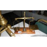 A set of small brass scales on wooden base complete with 6 graduated brass weights