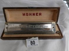 A cased Hohner 64 Chromonica professional harmonica