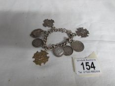 A silver bracelet with fobs and coins including one 9ct gold fob