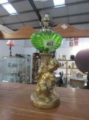 A gilded spelter cherub oil lamp with green glass font