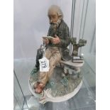 A signed Capo-di-monte figure of a man sat on a bench reading