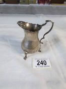 A silver cream jug with cabriole legs,