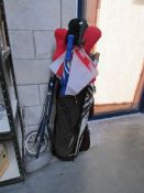A golf bag, trolley, clubs and umbrellas