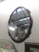 An oval mirror in wood frame