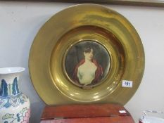 A brass plaque with a portrait of a lady