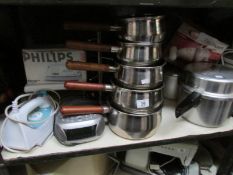 A shelf of kitchen ware including stainless steel pans