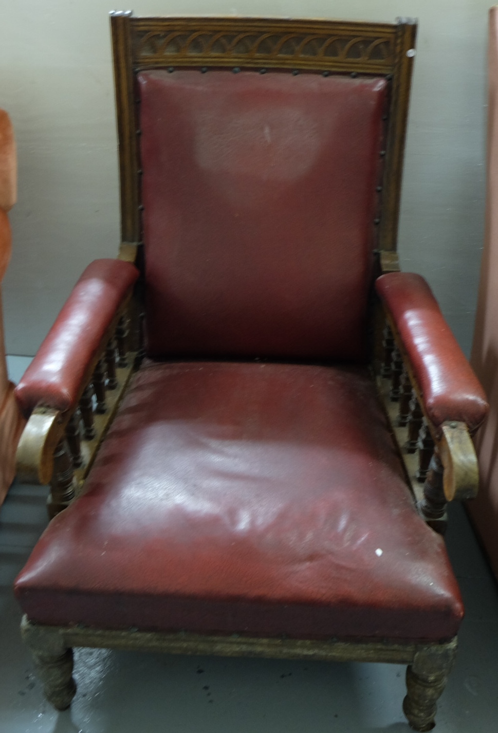 Edwardian Oak Framed Library Armchair, red leatherette seat and back, on turned front feet, castors