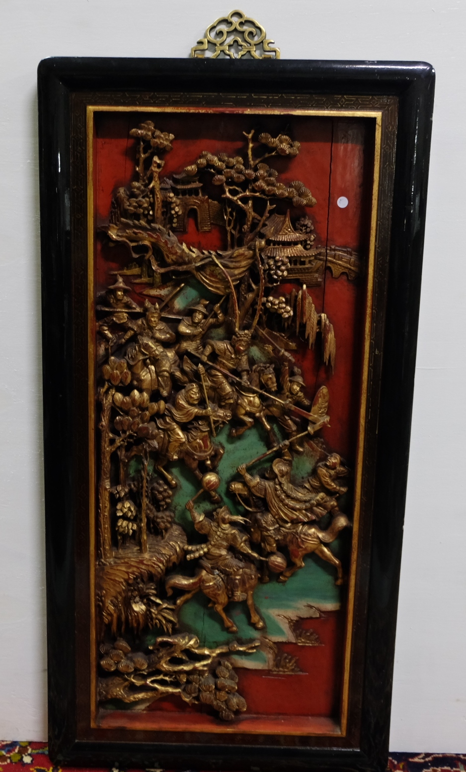 Carved Oriental Wall Plaque – gold painted raised figures of warriors on horseback, red