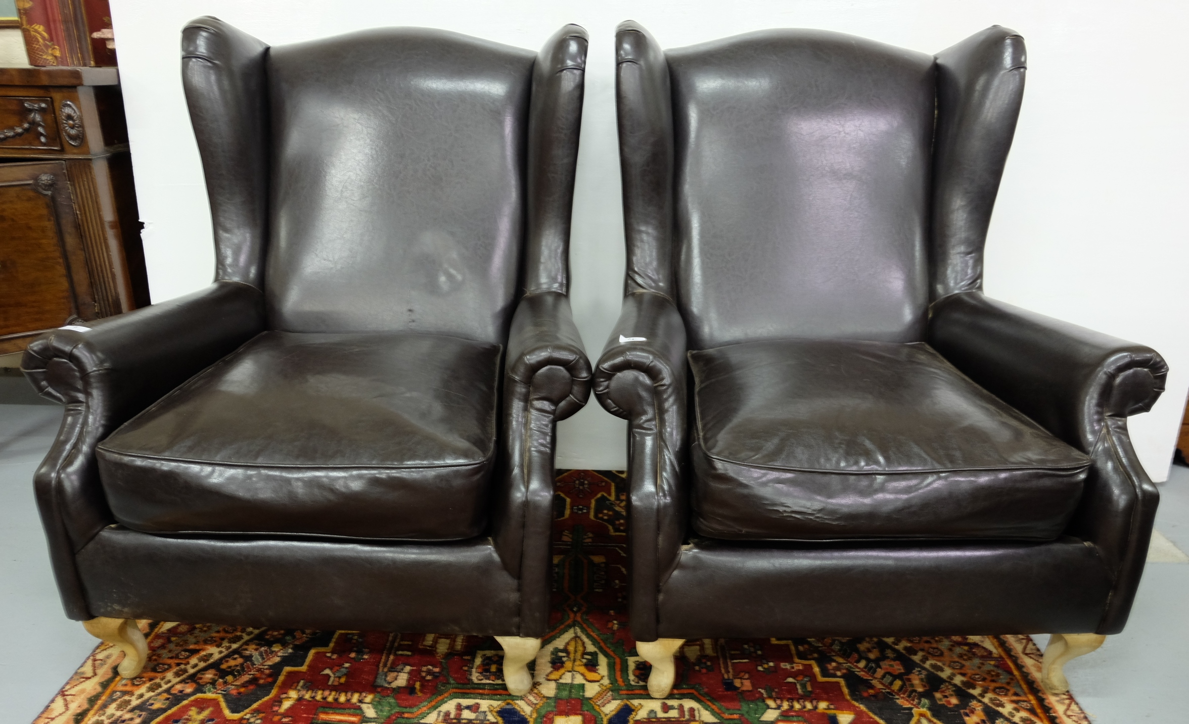 Matching Pair of Wingback Armchairs, covered in brown leatherette fabric, on cabriole legs,