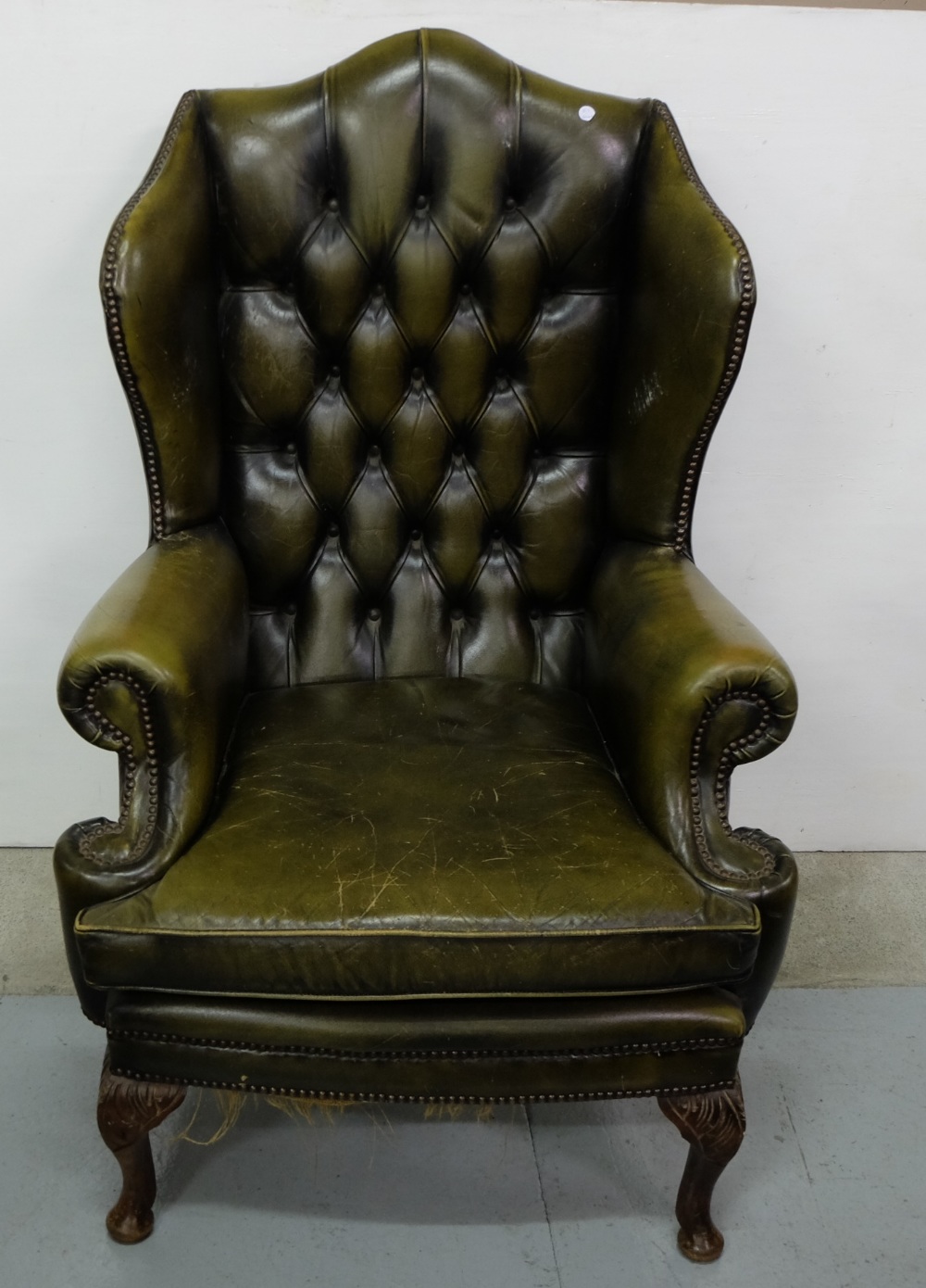 Green Leather Covered Wingback Armchair, with buttoned back and loose cushioned seat, on Queen Ann