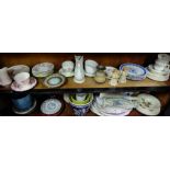 Two Shelves of china items – colourful cups, saucers, pair cherubs, oval plates etc