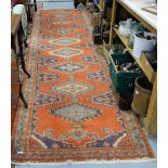 Long burnt orange ground runner, with medallion designs, 4.20m x 1.10 m