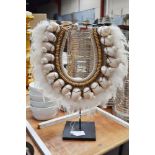 A traditional Papuan shell and feather necklace on a metal stand, approx 42cm H